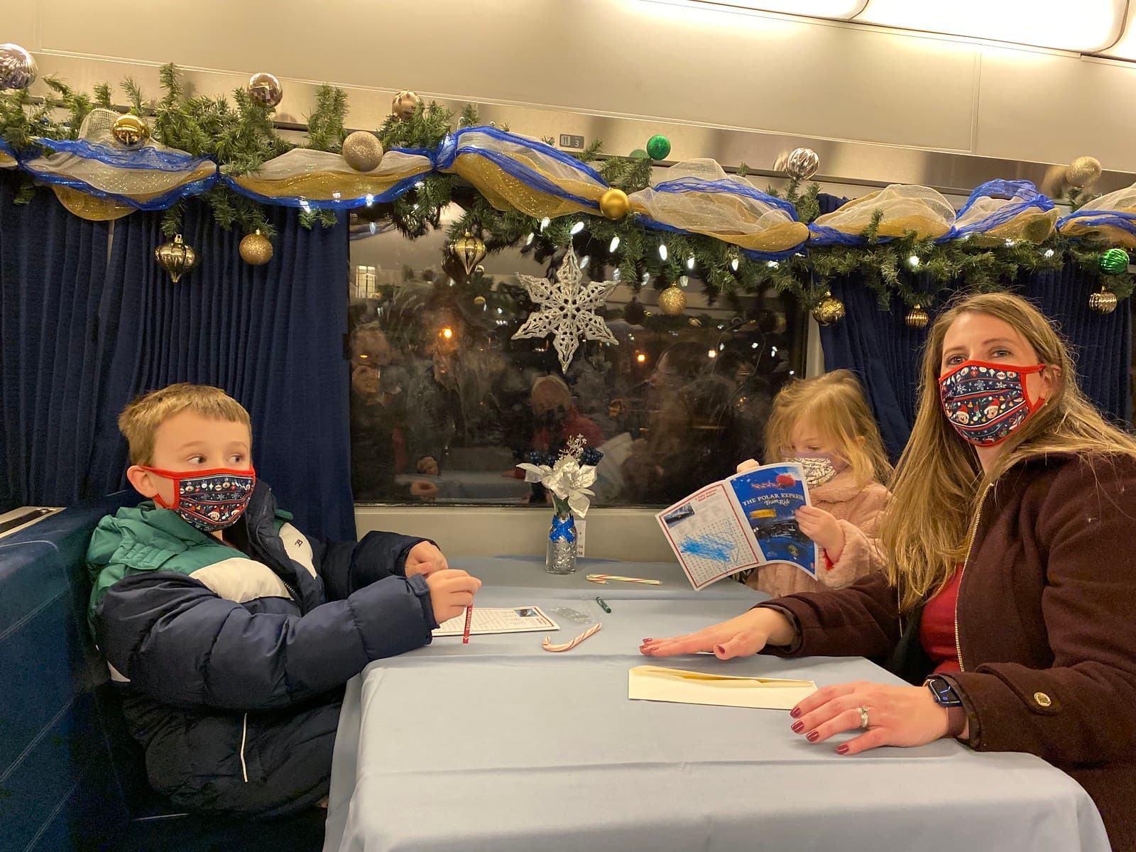 Passengers at a table inside a Christmas-decorated Adirondack Polar Express coach