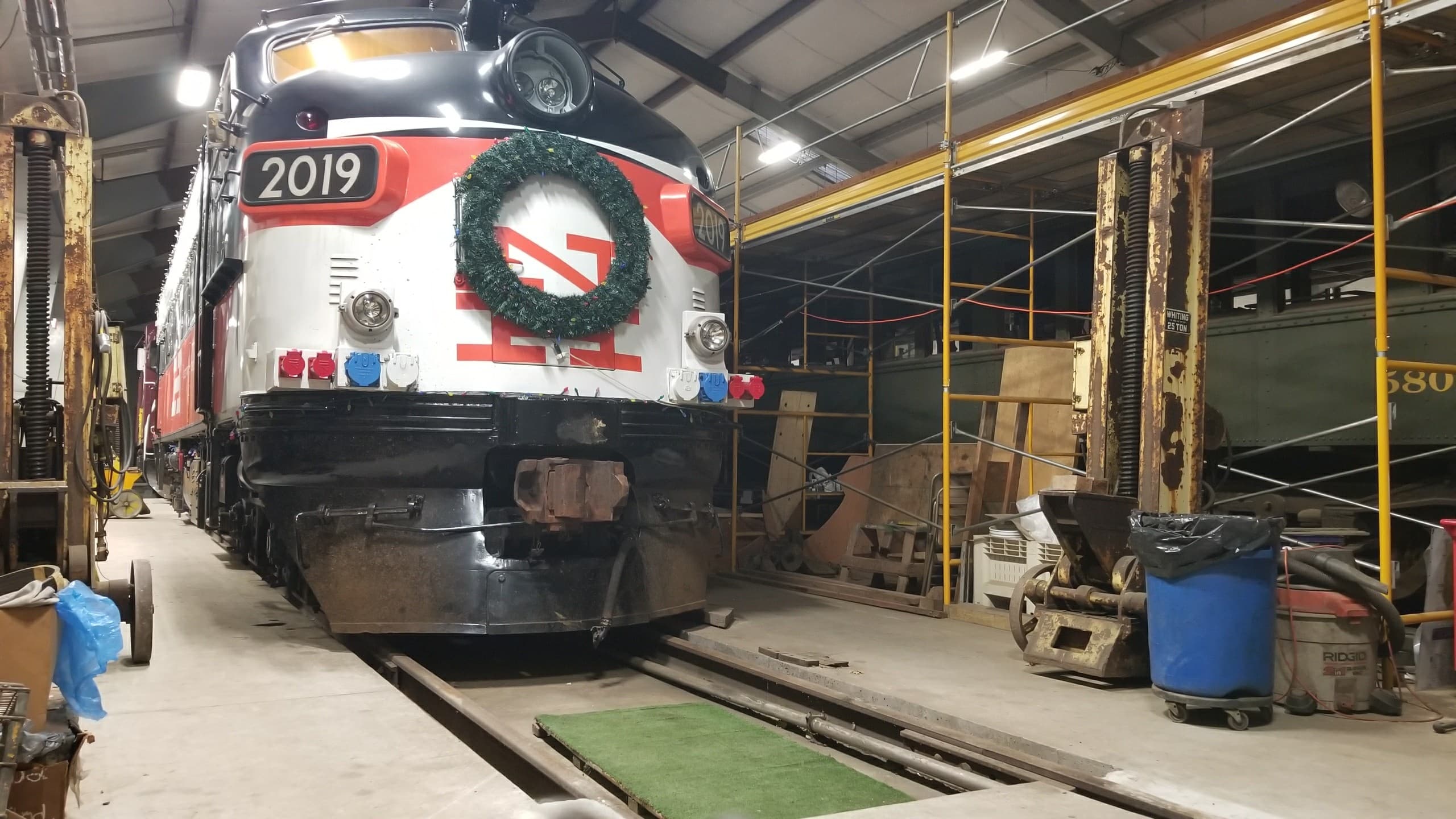 New Haven FL9 locomotive 2019 wearing a Christmas wreath inside a Railroad Museum of New England workshop